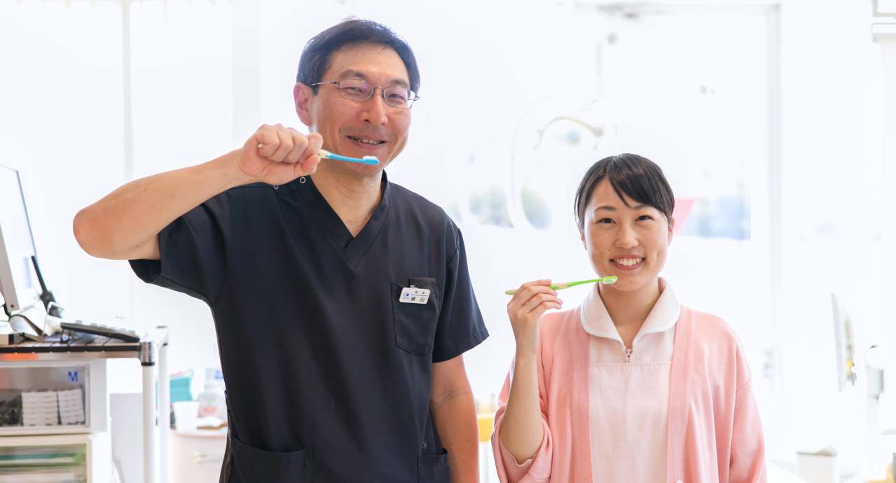 歯科医師とスタッフが歯ブラシを持って歯みがき指導をしている様子
